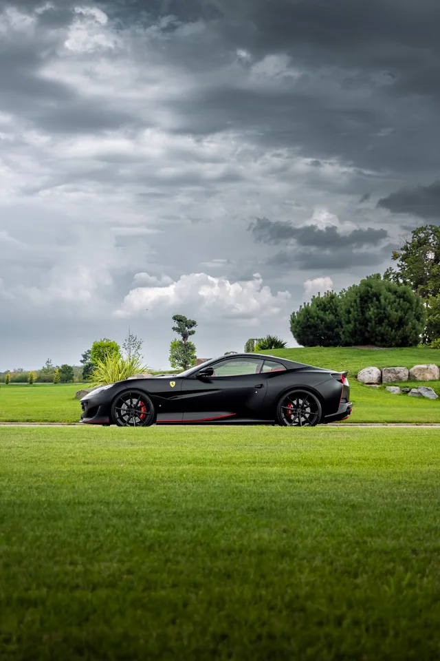 Black Ferrari against a green landscape